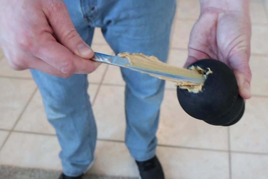 A kong toy with peanut butter being placed inside of it to reduce anxiety when leaving.
